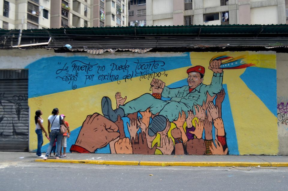 Mural que representa a Hugo Chávez sostenido por simpatizantes junto a la frase «La muerte no puede tocarte, estás por encima del tiempo», creado tras su fallecimiento en 2013. NEFTALIYAGUA