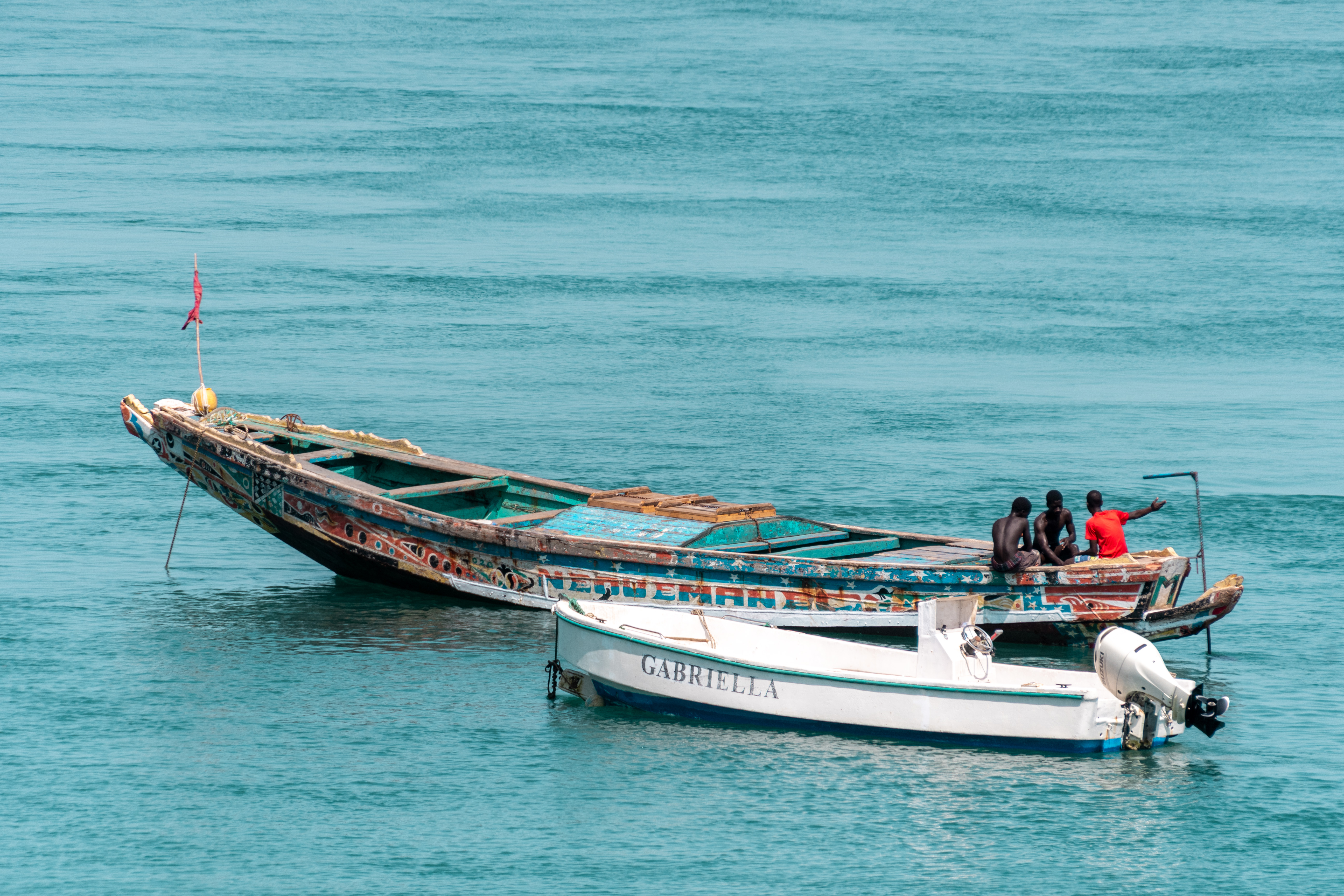 Tres jóvenes pescadores descansan sobre una canoa tradicional fondeada junto a una de las múltiples lanchas que los hoteles de la zona utilizan como transporte. JORGE FORNIELES