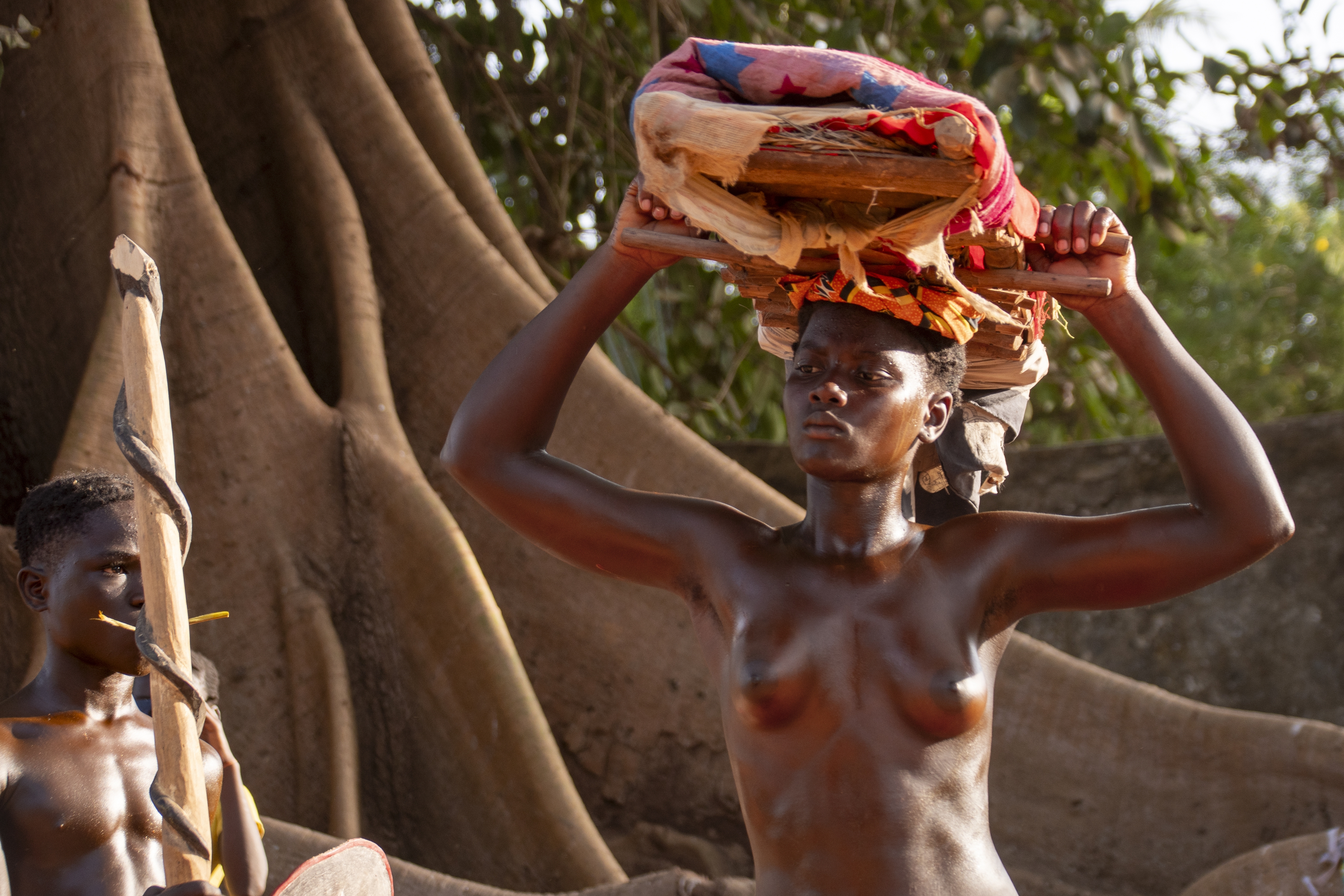Una joven embadurnada en aceite de palma porta una “cama de cansaré”, objeto que se entrega como ofrenda para tratar con las deidades locales. JORGE FORNIELES