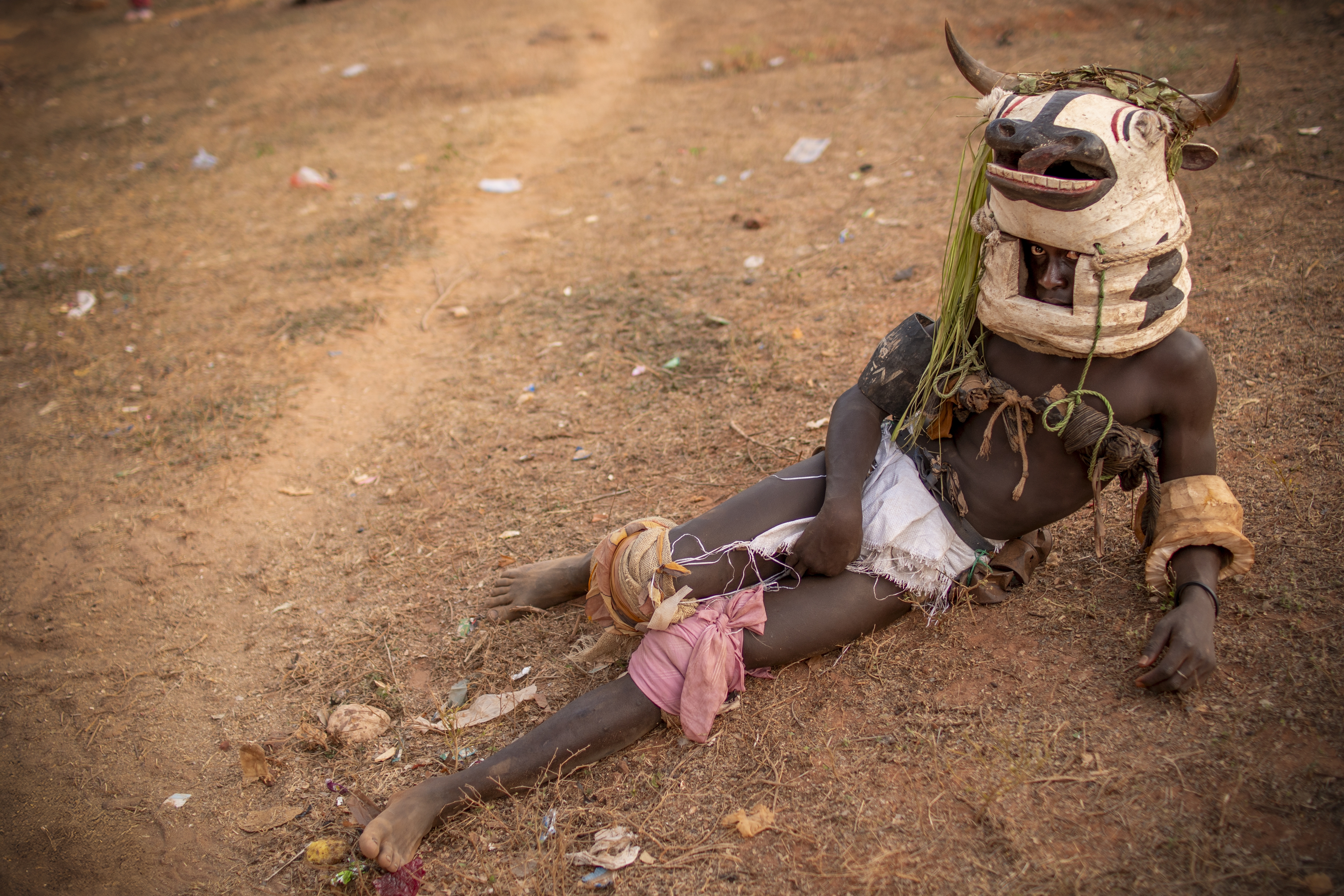 Un hombre vaca, ataviado con la tradicional máscara descansa tumbado en el suelo antes de la actuación de su agrupación. JORGE FORNIELES