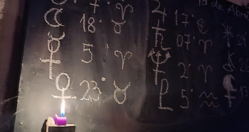 Una vela ilumina los símbolos astrológicos utilizados en los encuentros grupales. CORTESÍA