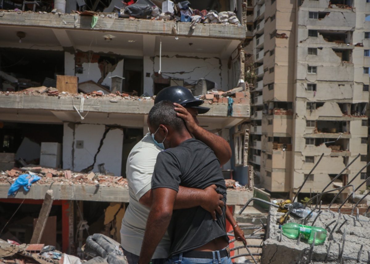 Dos vecinos se abrazan frente a uno de los edificios del complejo habitacional Luisa Cáceres de Arismendi, en Catia La Mar (La Guaira), tras el doble terremoto. DANIEL HERNÁNDEZ