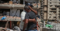 Dos vecinos se abrazan frente a uno de los edificios del complejo habitacional Luisa Cáceres de Arismendi, en Catia La Mar (La Guaira), tras el doble terremoto. DANIEL HERNÁNDEZ