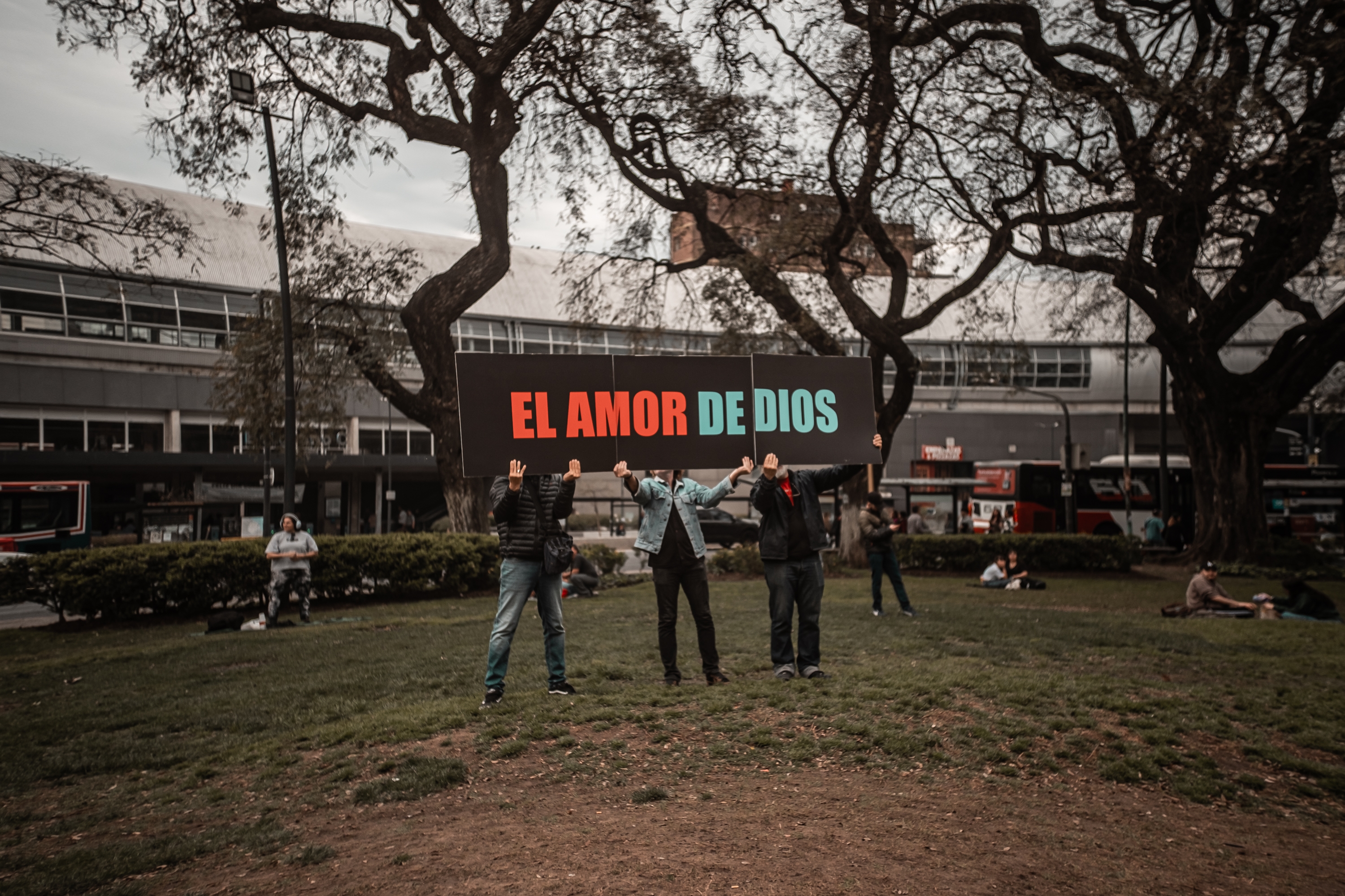 Un grupo religioso levanta un cartel con el mensaje «El amor de Dios» cerca del lugar donde los jóvenes celebran las batallas de aura. DANIELLA FERNÁNDEZ Un grupo religioso levanta un cartel con el mensaje «El amor de Dios» cerca del lugar donde los jóvenes celebran las batallas de aura. DANIELLA FERNÁNDEZ