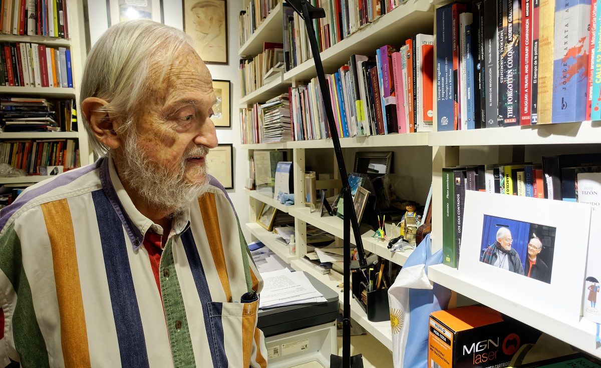 El editor argentino Daniel Divinsky, en su casa de Buenos Aires, contempla una foto de él con Quino. EDUARDO HOJMAN