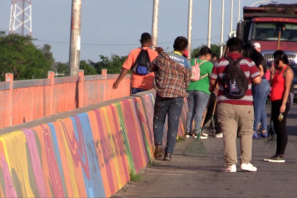 Jóvenes pasan junto a los murales que decoran el puente San Marcos Lempa, en El Salvador. LUIS BRUZÓN DELGADO