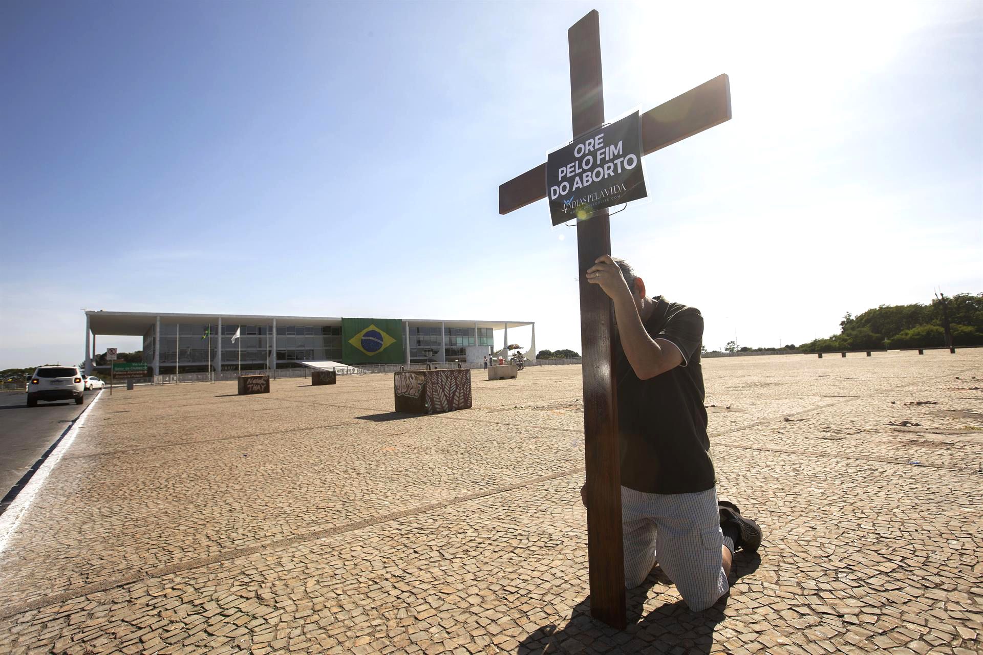 Un hombre reza con una cruz en la Plaza de los Tres Poderes, en Brasilia, el 15 de octubre de 2022. EFE/JOEDSON ALVES