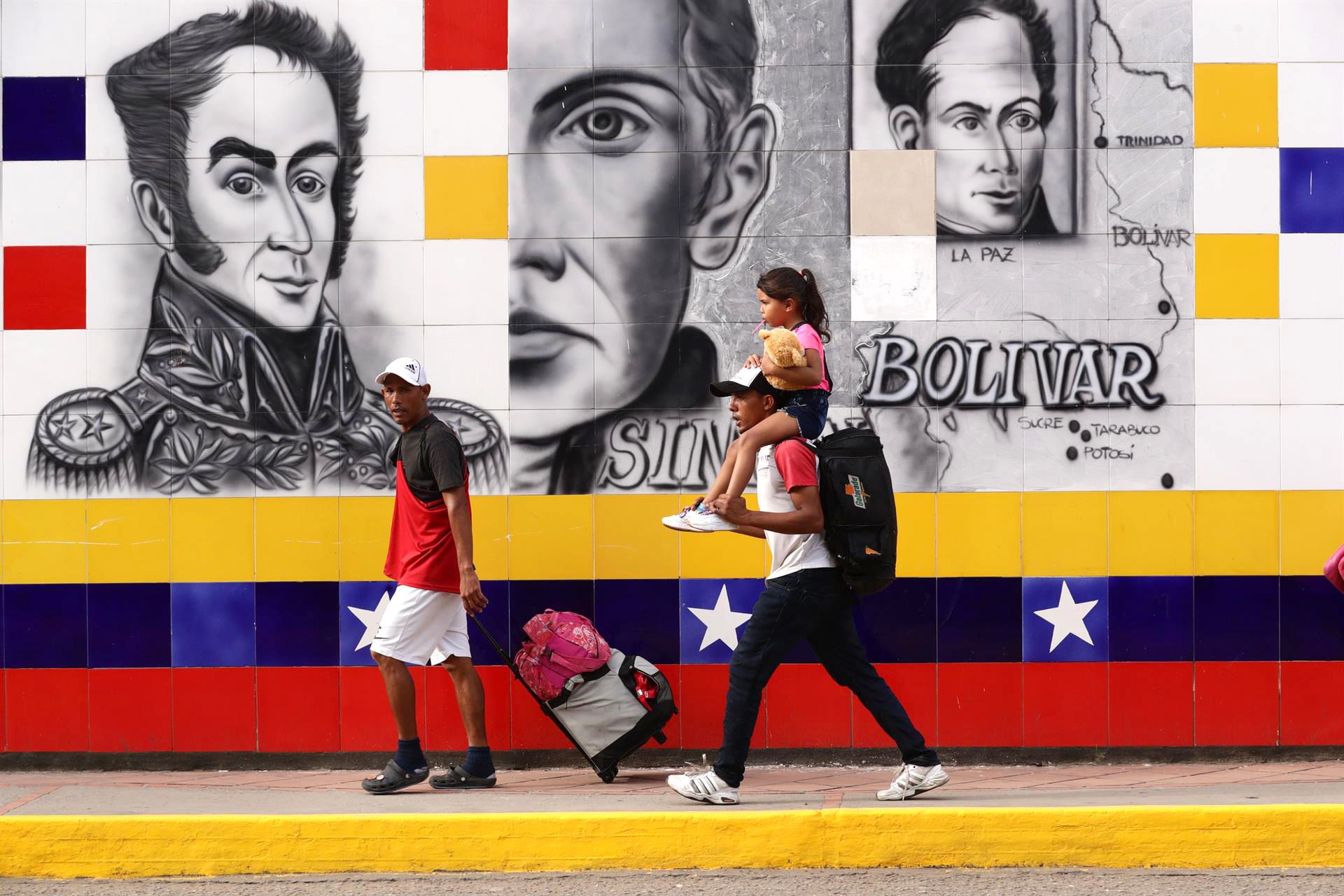 Personas cruzan el Puente Simón Bolívar, en la frontera entre Venezuela y Colombia, ante un mural con la imagen del Libertador. EFE/RAYNER PEÑA