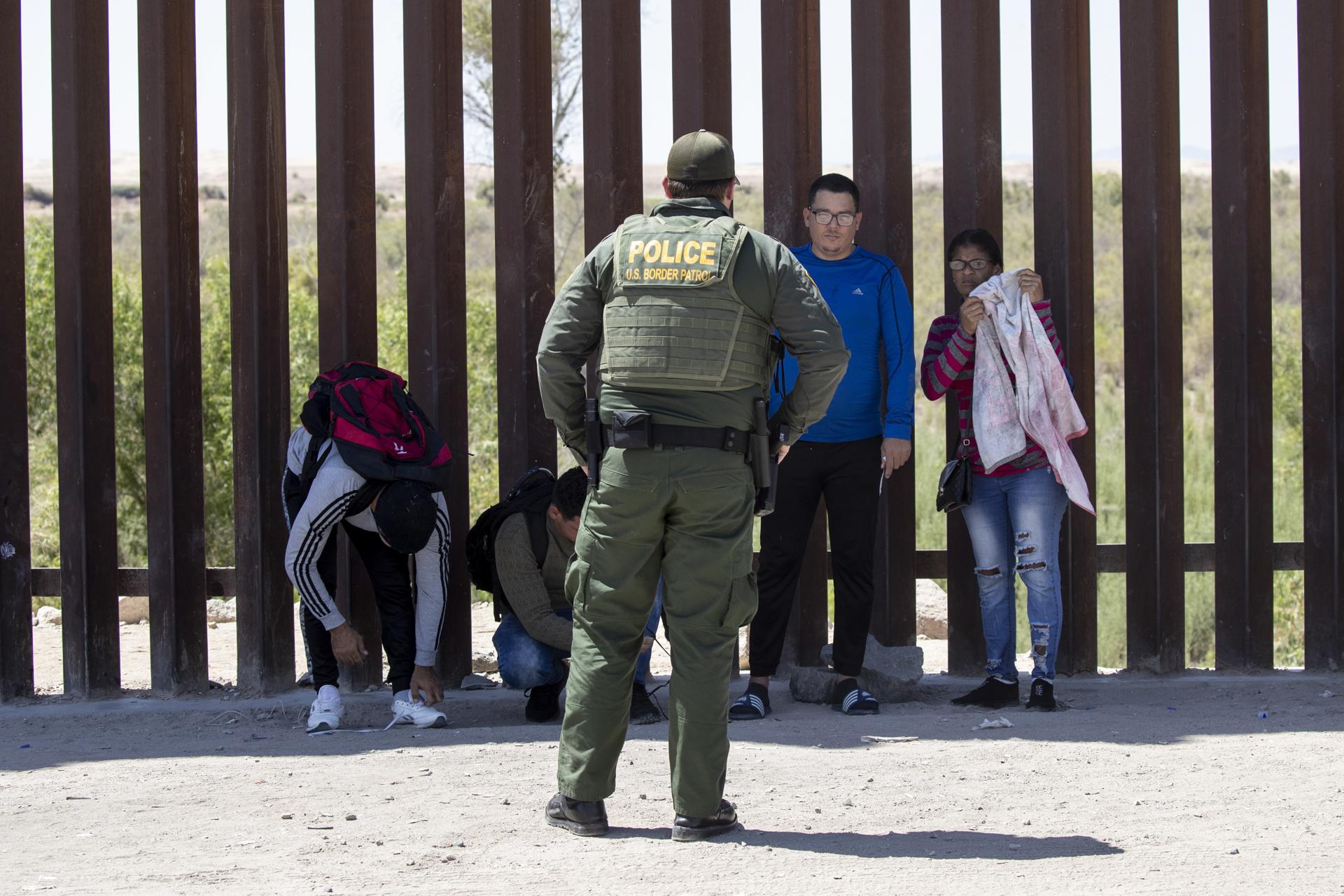 Un patrullero en la frontera entre México y Estados Unidos con unas personas migrantes. EFE/ETIENNE LAURENT