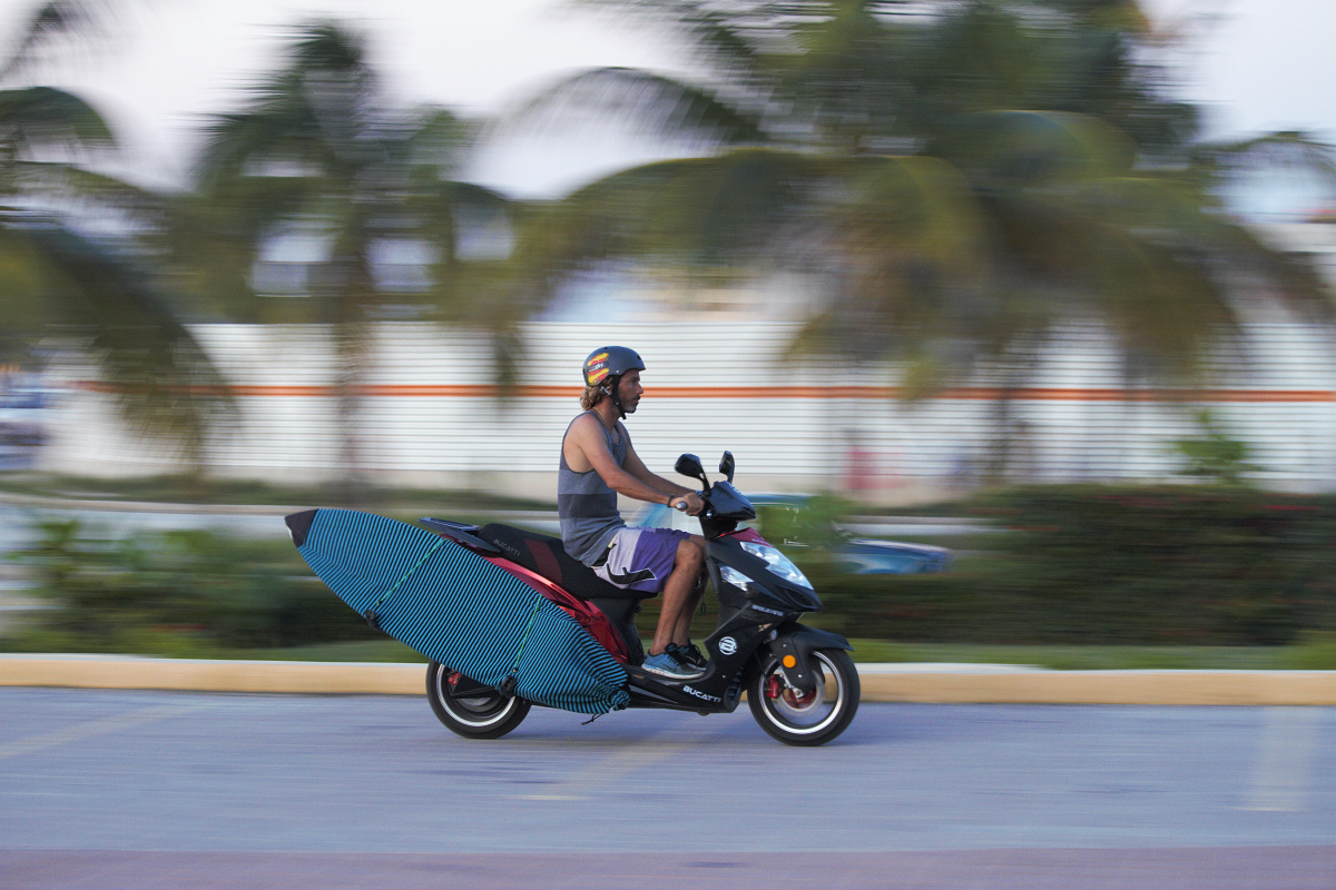 El surfista cubano Frank González, con su tabla a bordo de una motocicleta. YENIA EXPÓSITO