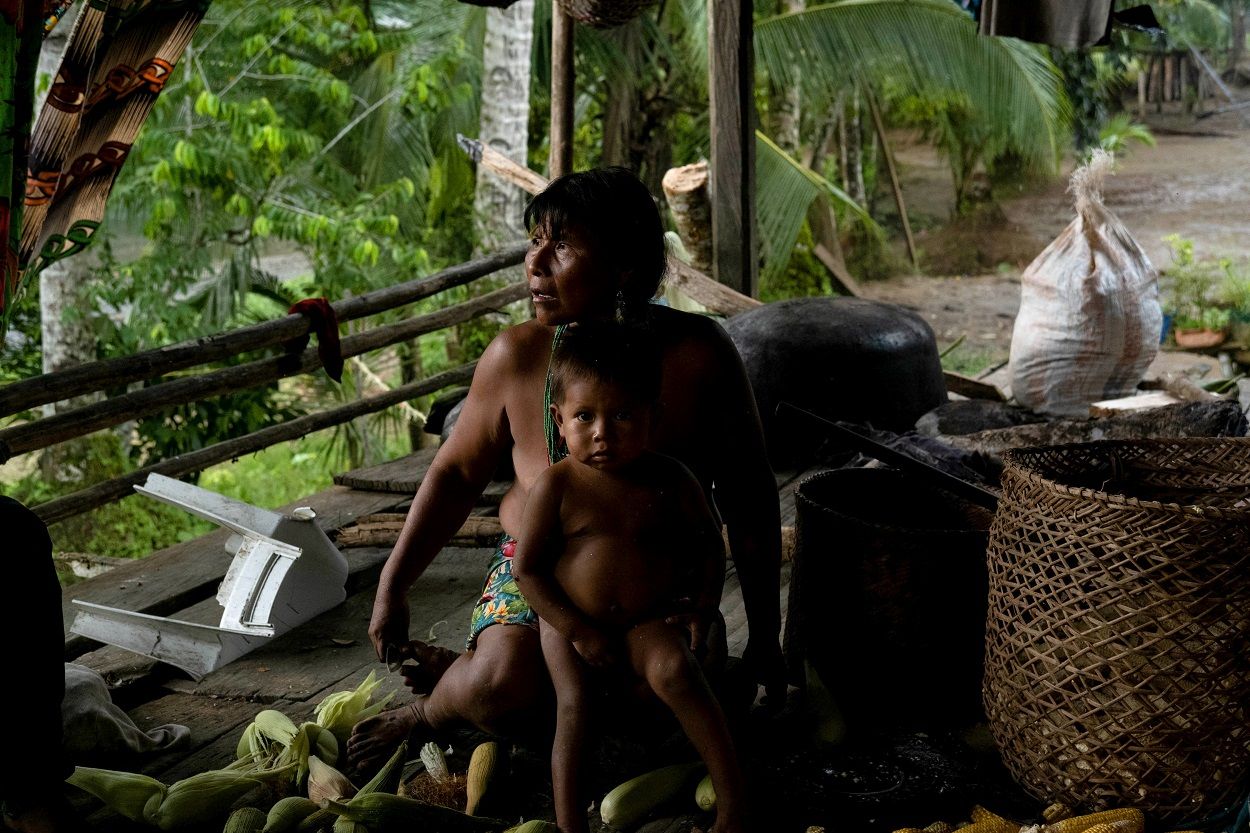 La madre de una joven Emberá Dobida que se suicidó, con su nieto mientras pela el maíz para hacer chicha y masa de choclo. MARIO TORO QUINTERO