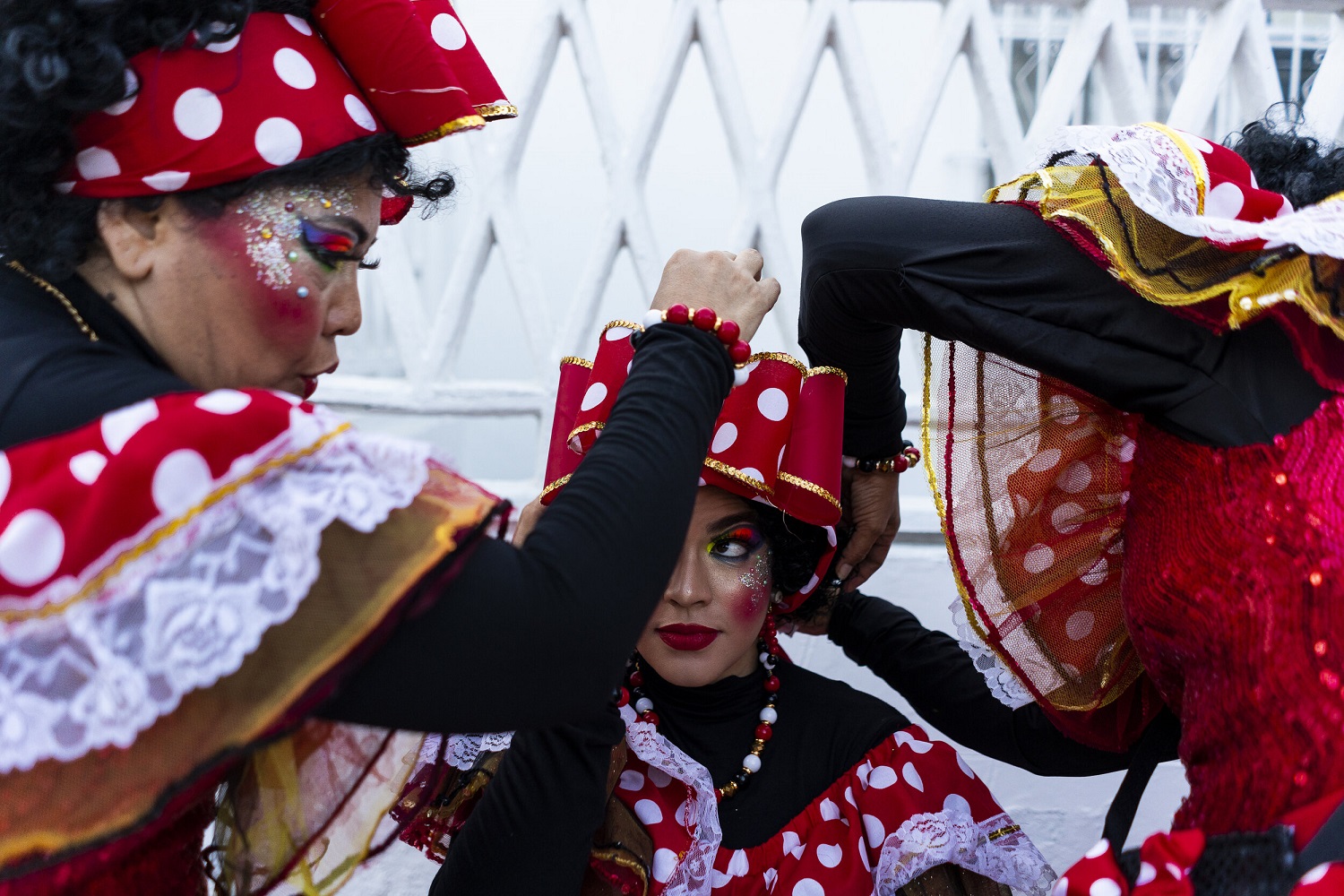 Integrantes de la compañía Negritas Puloy del carnaval de Barranquilla ayudan a una bailarina a colocarse el disfraz. CHARLIE CORDERO