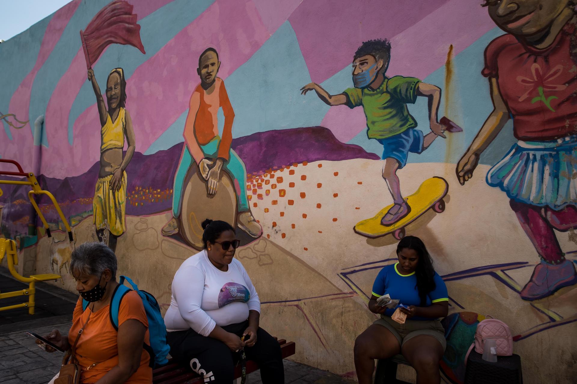 Mujeres frente a un mural sobre afrodescendientes, el 16 de marzo, en Caracas, Venezuela. EFE/MIGUEL GUTIÉRREZ