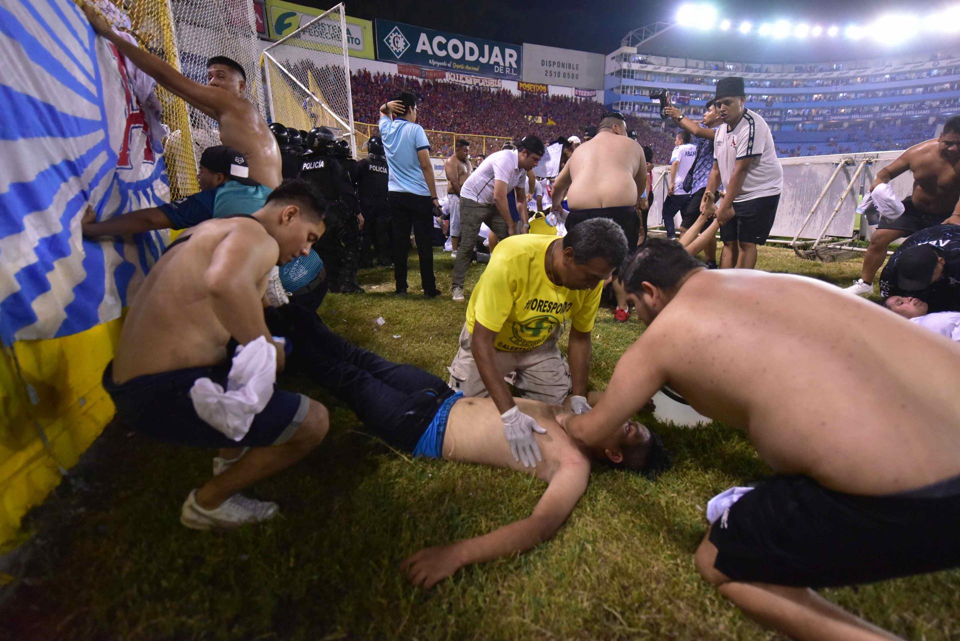 Asistentes al estadio Cuscatláán de San Salvador auxilian a un herido tras la estampida, este 20 de mayo de 2023. EFE/MIGUEL LEMUS