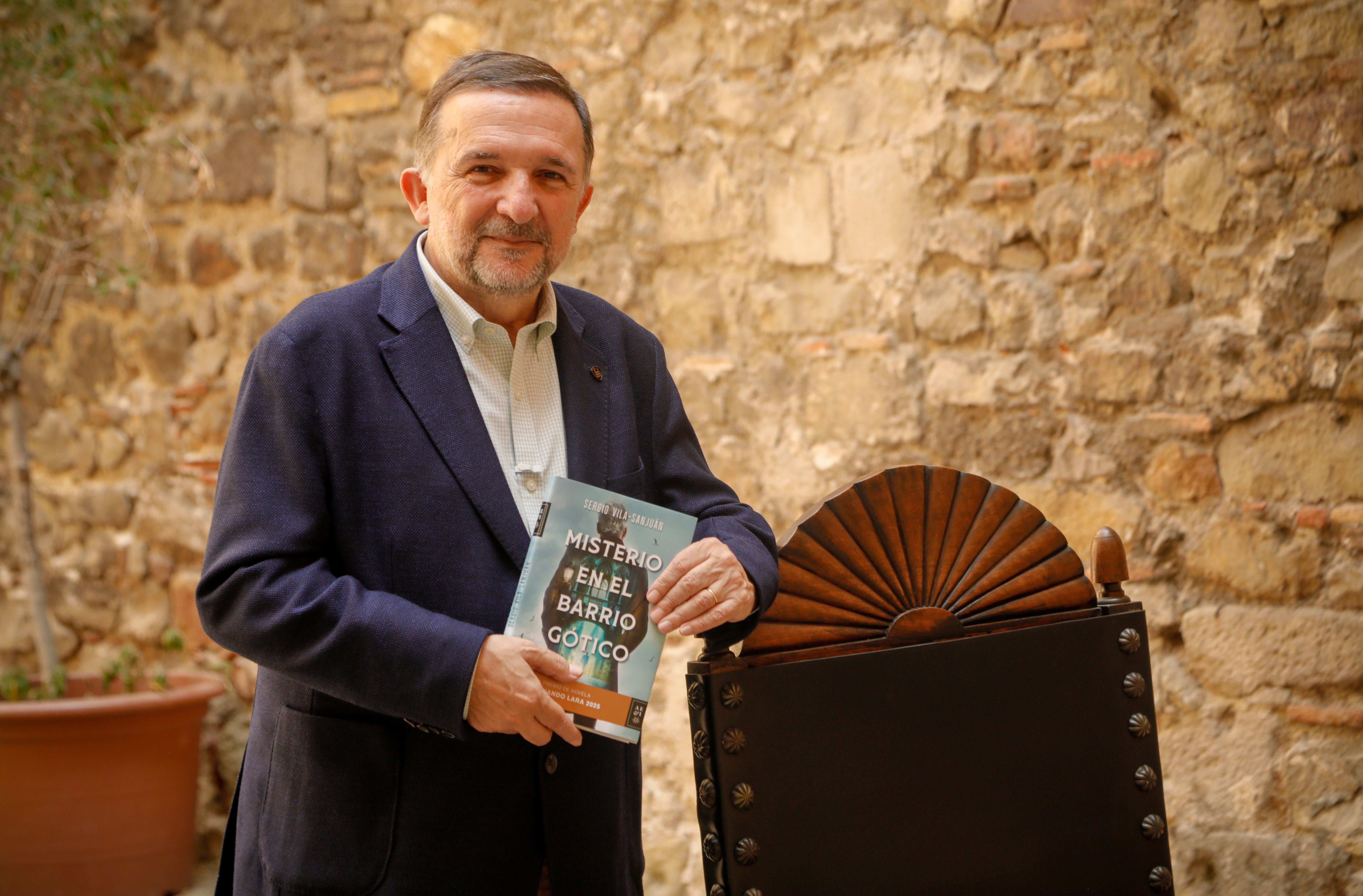 Sergio Vila‑Sanjuán posa con su novela ganadora del Premio Fernando Lara 2025, 'Misterio en el Barrio Gótico'. JAVIER OCAÑA