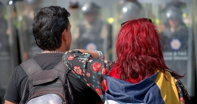 Dos venezolanos frente a la policía en Caracas, en un país donde la represión y la crisis han alimentado una diáspora que supera ya los nueve millones de migrantes. CARLOS DÍAZ